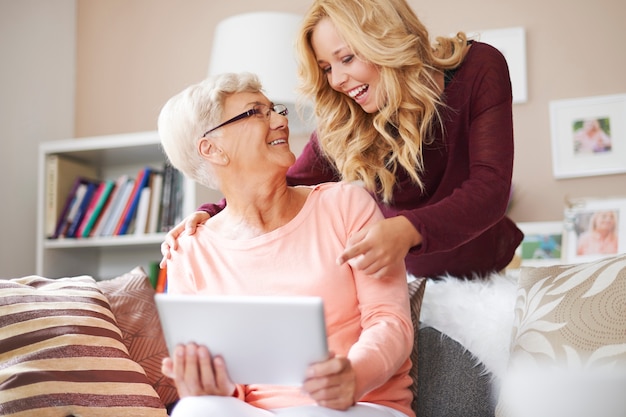 Süßes blondes Mädchen, das etwas Lustiges auf digitalem Tablett zeigt