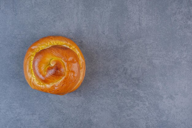 Süßes Brötchen, das aufrecht auf Marmorhintergrund steht. Foto in hoher Qualität