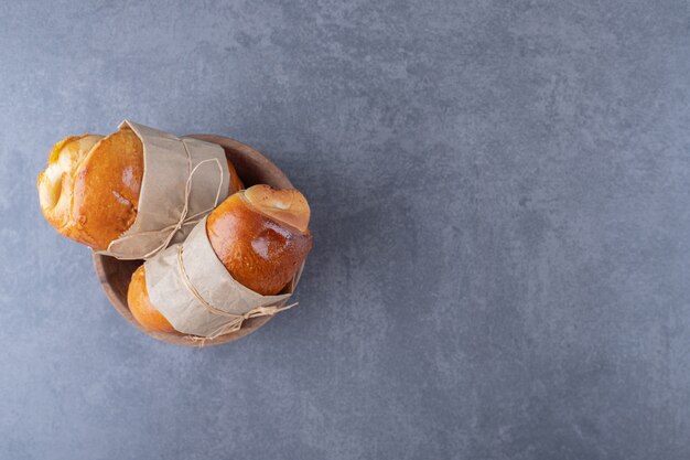 Süßes Brötchen mit einem Faden in einer Schüssel auf Marmortisch gebunden.