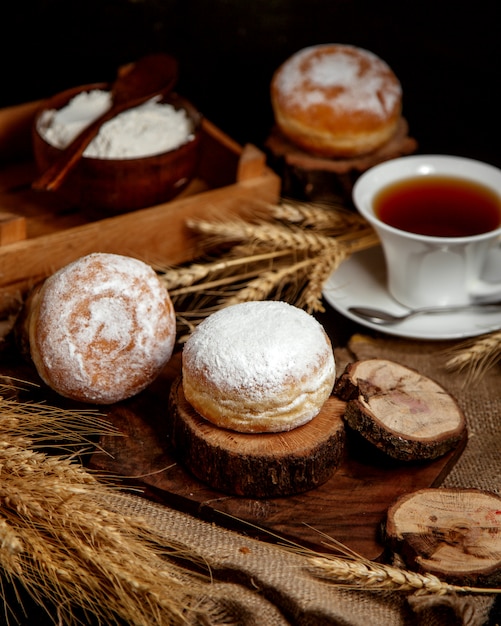 Süßes Brötchen mit Puderzucker und einer Tasse Tee bestreut