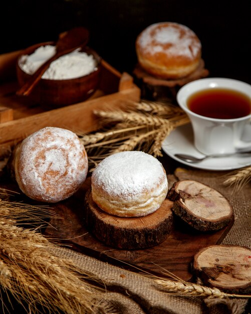 Süßes Brötchen mit Puderzucker und einer Tasse Tee bestreut