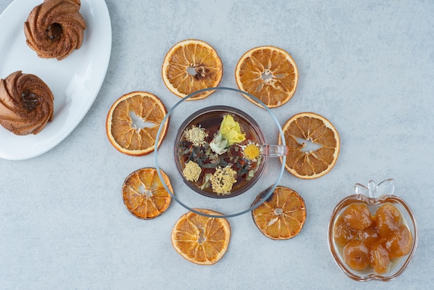 Süßes Gebäck mit getrockneter Orange und Tasse Kräutertee auf Marmorhintergrund. Hochwertiges Foto