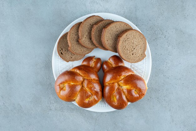 Süßes Gebäck und Brotscheiben auf weißem Teller.