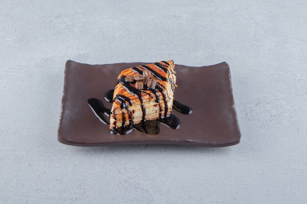 Süßes Gebäck verziert mit Schokolade auf dunklem Teller. Foto in hoher Qualität