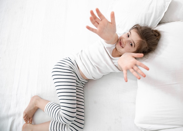 süßes kleines Mädchen schläft in einem weißen Bett.