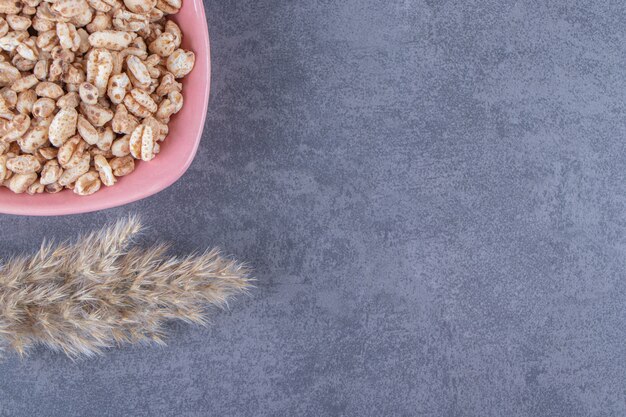 Süßes Müsli in einer Schüssel neben Pampasgras, auf dem blauen Tisch.