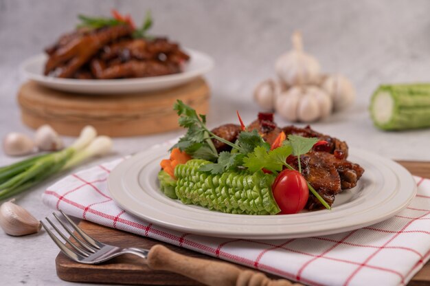 Süßes Schweinefleisch in einem weißen Teller mit gehackten Frühlingszwiebeln, Chili, Limette, Kürbis, Tomate und Knoblauch.