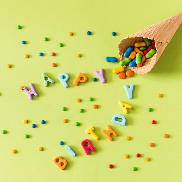 Süßigkeiten, die Waffeleiskegel auf alles Gute zum Geburtstag über grüner Oberfläche überlaufen