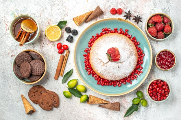 Süßigkeiten Kekse eine Tasse Tee einen Kuchen Zimtstangen Beeren Zitrusfrüchte