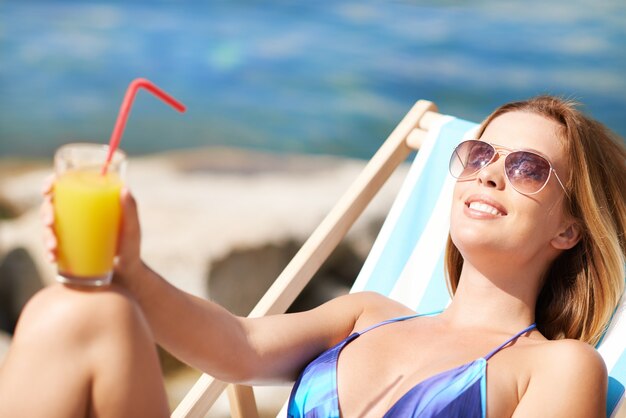 Sunbathed Frau mit einem Orangensaft