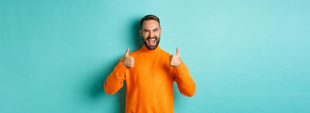 Kostenloses Foto super guter, zufriedener, glücklicher mann, der daumen hoch zeigt, stimme mit ihnen überein, loben sie die hervorragende arbeit, die sie bitte sehen