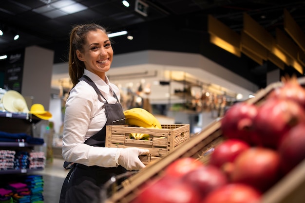 Supermarktarbeiter, der die Obstabteilung mit Lebensmitteln versorgt