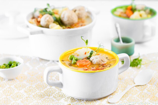 Suppe mit Fleischbällchen Blumenkohl Erbsen Karotten und Sahne auf weißem Hintergrund