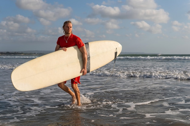 Surfer, der am Strand entlang geht. bali