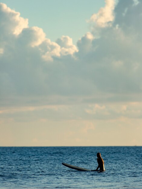 Surfer, der bei Sonnenuntergang im Meer sitzt