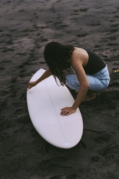 Kostenloses Foto surfer der jungen frau, der ein surfbrett auf dem ozean vorbereitet, der wächst frau mit surfbrett auf dem ozean aktiver lebensstil wassersportarten