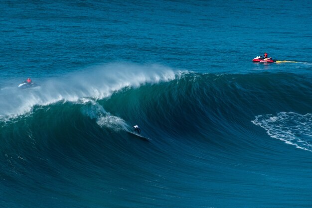 Surfer reiten auf den Wellen des Atlantischen Ozeans in Richtung der Küste von Nazare, Portugal