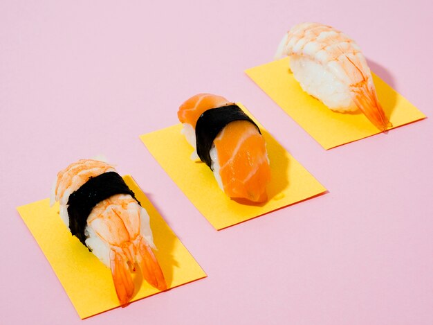 Sushi auf gelben Papieren auf rosafarbenem Hintergrund