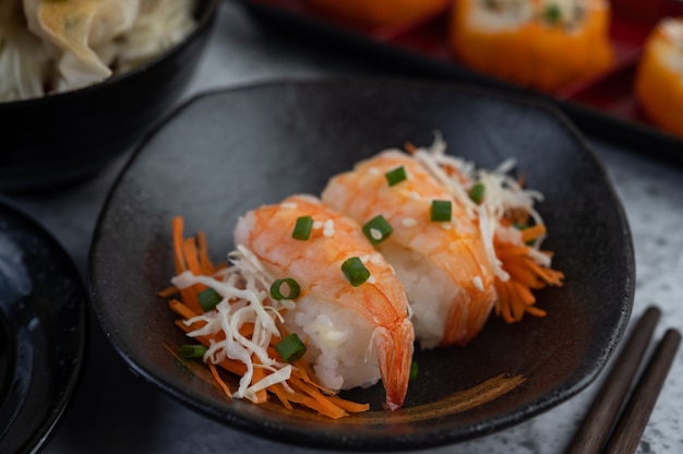 Sushi ist in einem Teller mit Stäbchen und Dip auf einem weißen Zementboden.