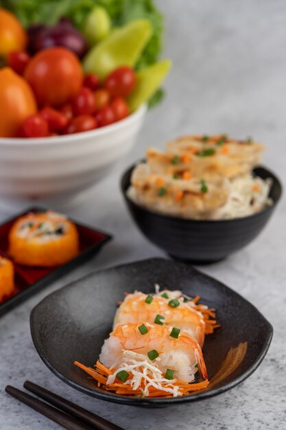 Sushi ist in einem Teller mit Stäbchen und Dip auf einem weißen Zementboden.