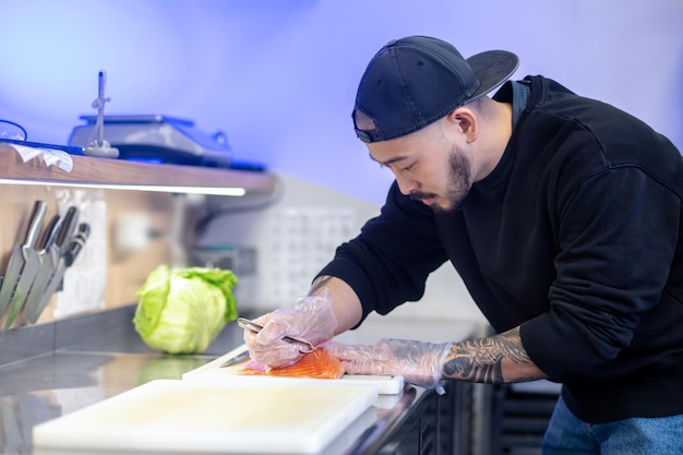 Sushi-Koch schneidet Fisch und macht Sushi