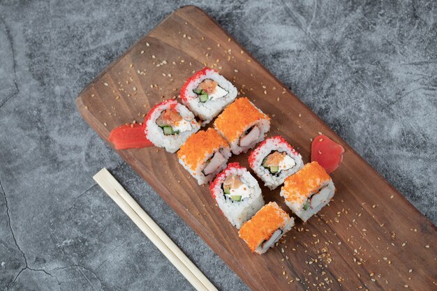 Sushi Maki mit rotem Kaviar und Frischkäse auf einem Holzbrett.