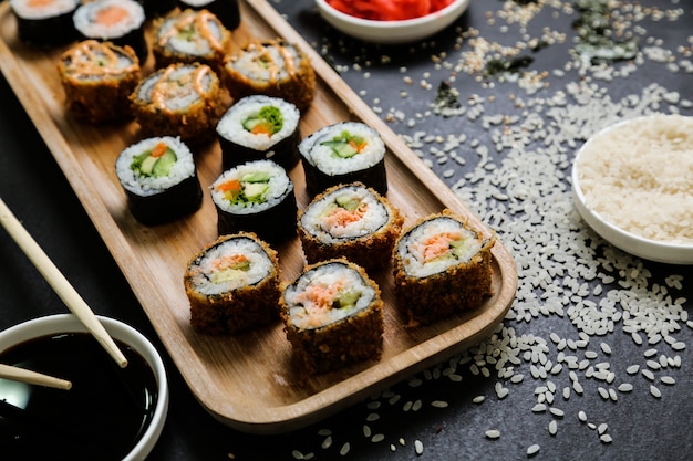 Sushi mit Gurke, Ingwer, Wasabi, Sojasauce und Sesam