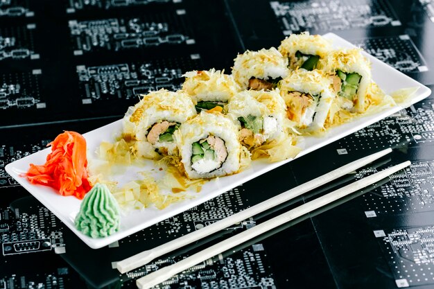 Sushi-Rollen mit gekochtem Lachs und Gurke, serviert mit Ingwer und Wasabi