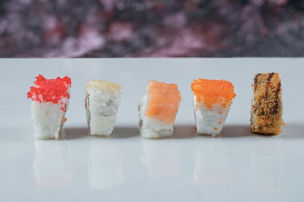 Sushi-Rollen mit gemischten Bestandteilen lokalisiert auf weißem Tisch.