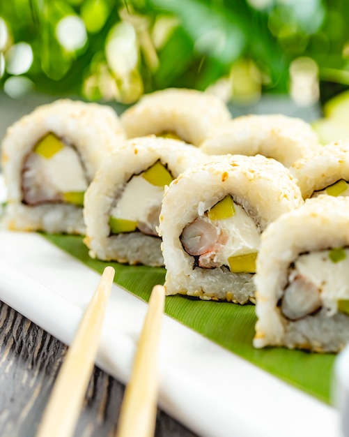 Sushi-Rollen mit Reis, Garnelen, Avocado und Frischkäse mit Sojasauce auf dem Tisch