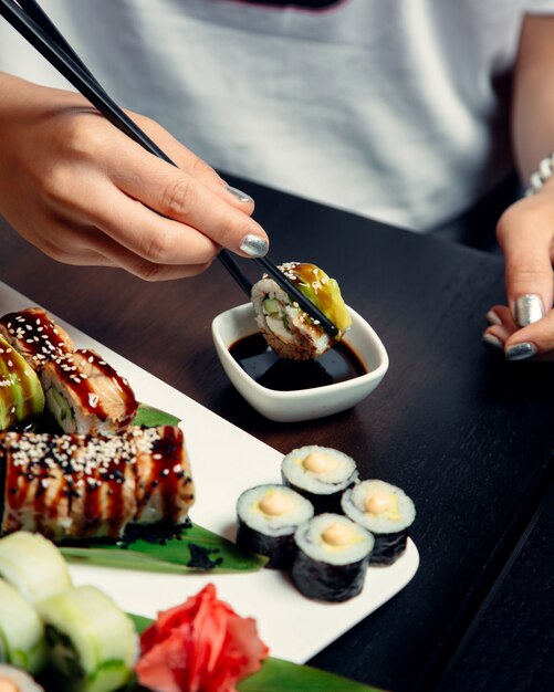 Sushi-Rollen mit Sauce und Sesam belegt