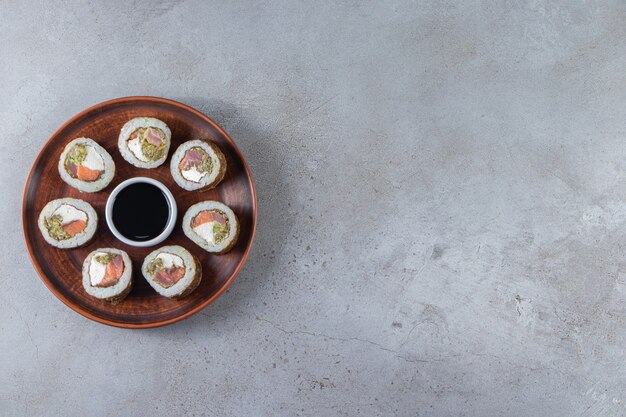 Sushi-Rollen mit Sojasauce auf eine Holzplatte gelegt.