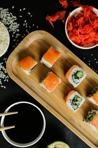 Sushi-Rollen serviert auf Holzteller mit Draufsicht auf klassische Zutaten