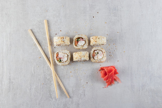 Sushi-Rollen, Sojasauce, Wasabi und eingelegter Ingwer auf Steinhintergrund.