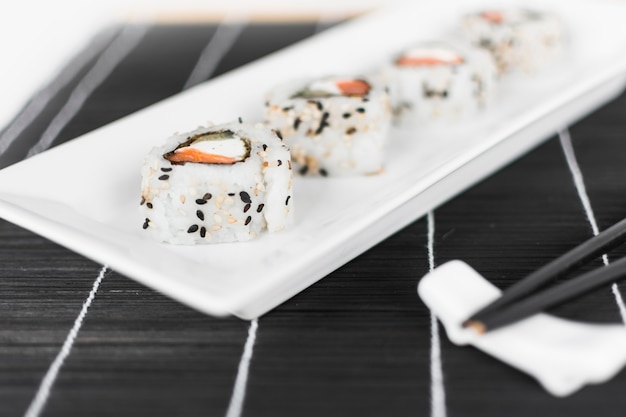 Sushirolle auf weißem Behälter mit Essstäbchen