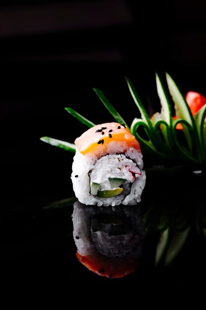 Sushirolle mit Lachs- und Frischkäse im dunklen Raum.