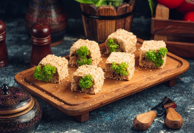 Sushirollen mit grüner Pistazie auf einem hölzernen Brett.