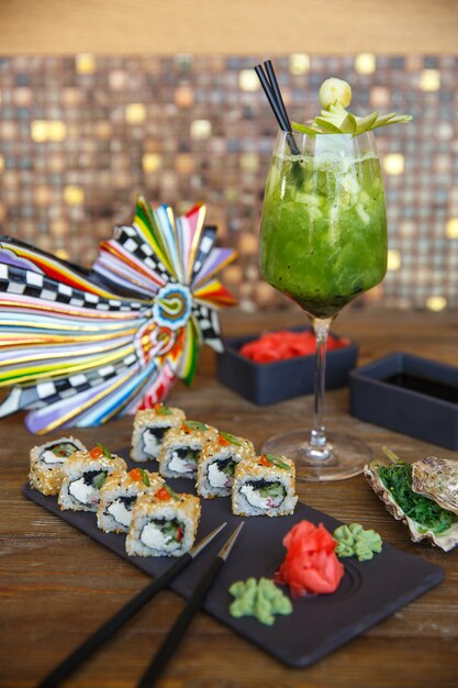 Sushirollen mit Sesam, serviert mit Ingwer und Wasabi, serviert mit Kiwi-Cocktail