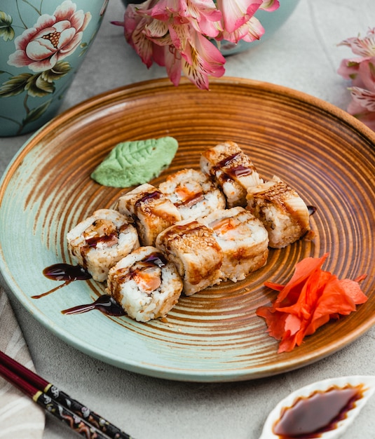 Sushirollen mit Sojasoße innerhalb der braunen blauen Platte.