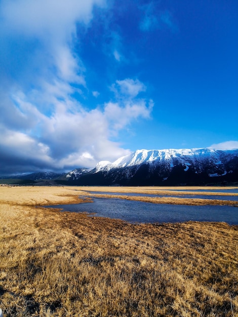 Szenische Ansicht eines Seeufers gegen einen schneebedeckten Berg und einen blauen Himmel