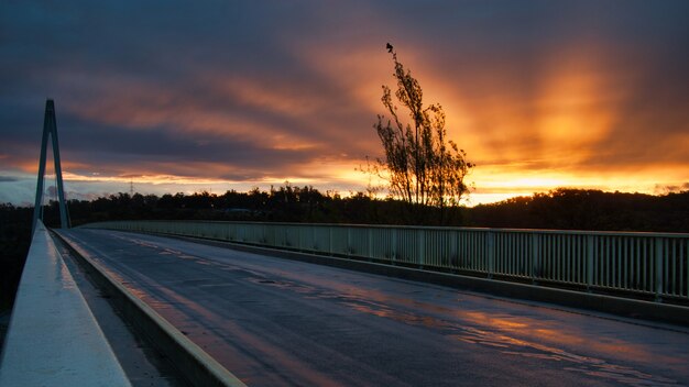 Szenische Aufnahme eines Sonnenuntergangs von einer Brücke mit schönen Strahlen, die von der Sonne ausstrahlen