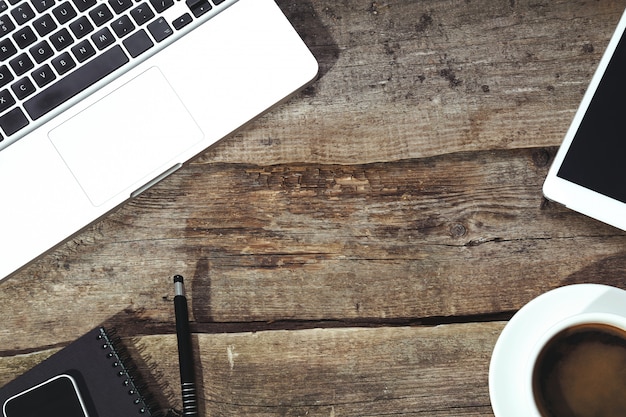 Tablet, Computer, Smartphone, Notizblock und Stift auf dem Tisch mit einer Tasse Kaffee