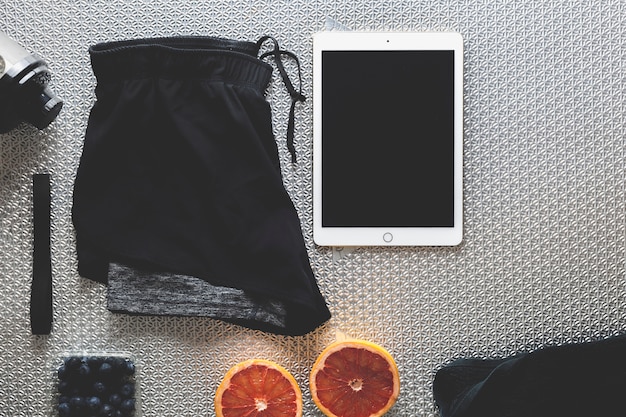 Tablet in der Nähe von Shorts und Früchten