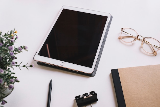 Tablet und Brille in der Nähe von Schreibwaren