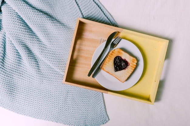 Tablett mit Toast mit Marmelade in Herzform auf dem Bett