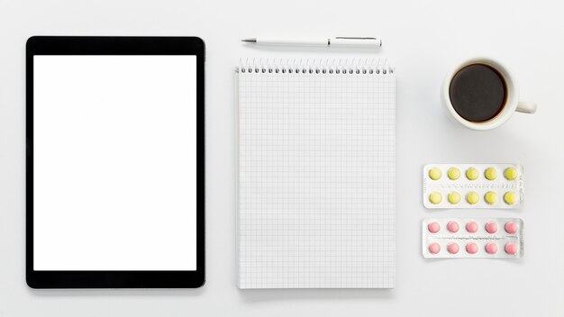 Tablette mit Notizbuch und Pillen