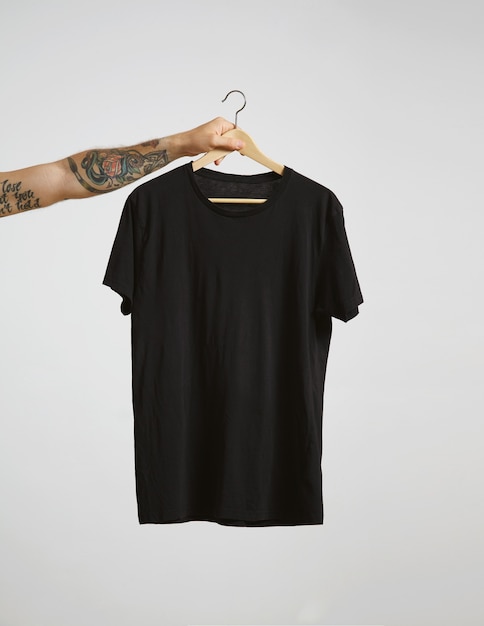 Tätowierte Biker-Handgriffe hängen mit leerem schwarzen T-Shirt aus hochwertiger dünner Baumwolle, isoliert auf Weiß