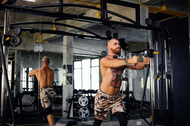 Tätowierter fitter Mann, der Übung im Fitnessstudio macht