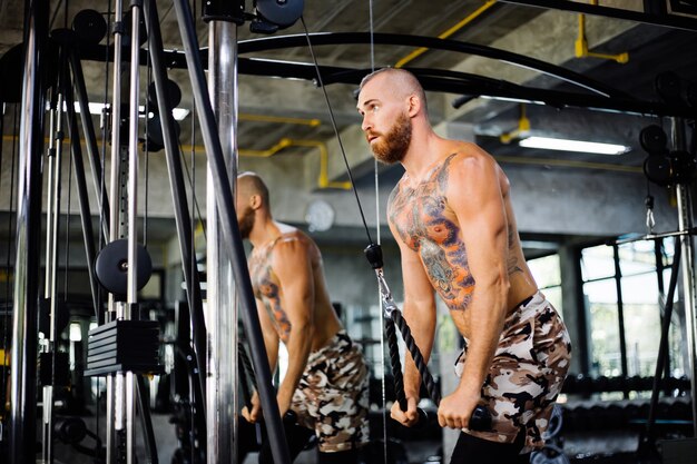 Tätowierter fitter Mann, der Übung im Fitnessstudio macht