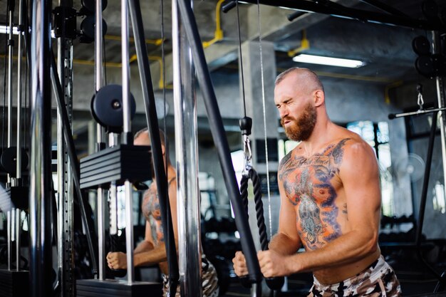 Tätowierter fitter Mann, der Übung im Fitnessstudio macht